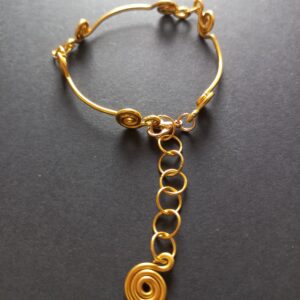Pulseira espirais realizada em fio de alumínio dourado com pendente de espiral